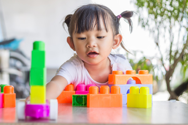 A young child playing with colourful plastic blocks of varying shapes and sizes